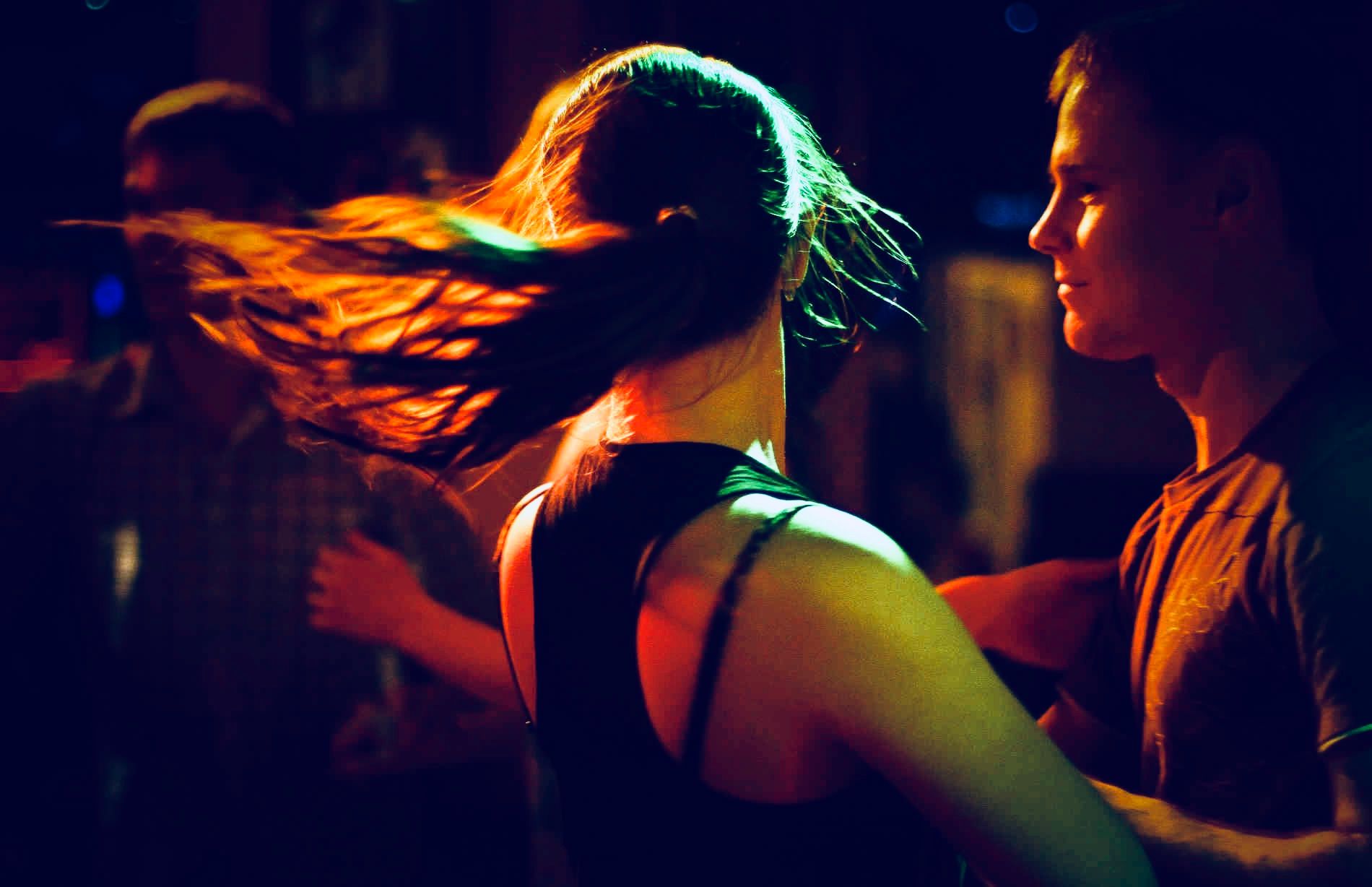 A couple dancing close under warm neon light