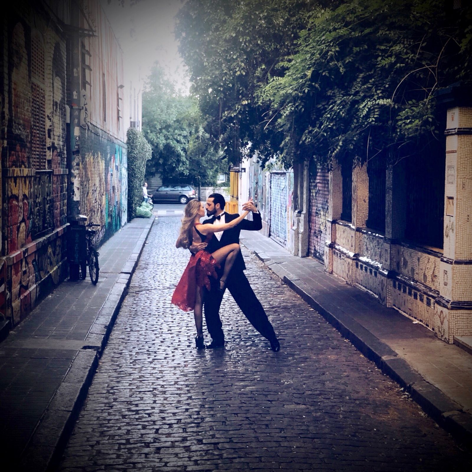 A couple dancing on a quiet cobblestone street at dusk