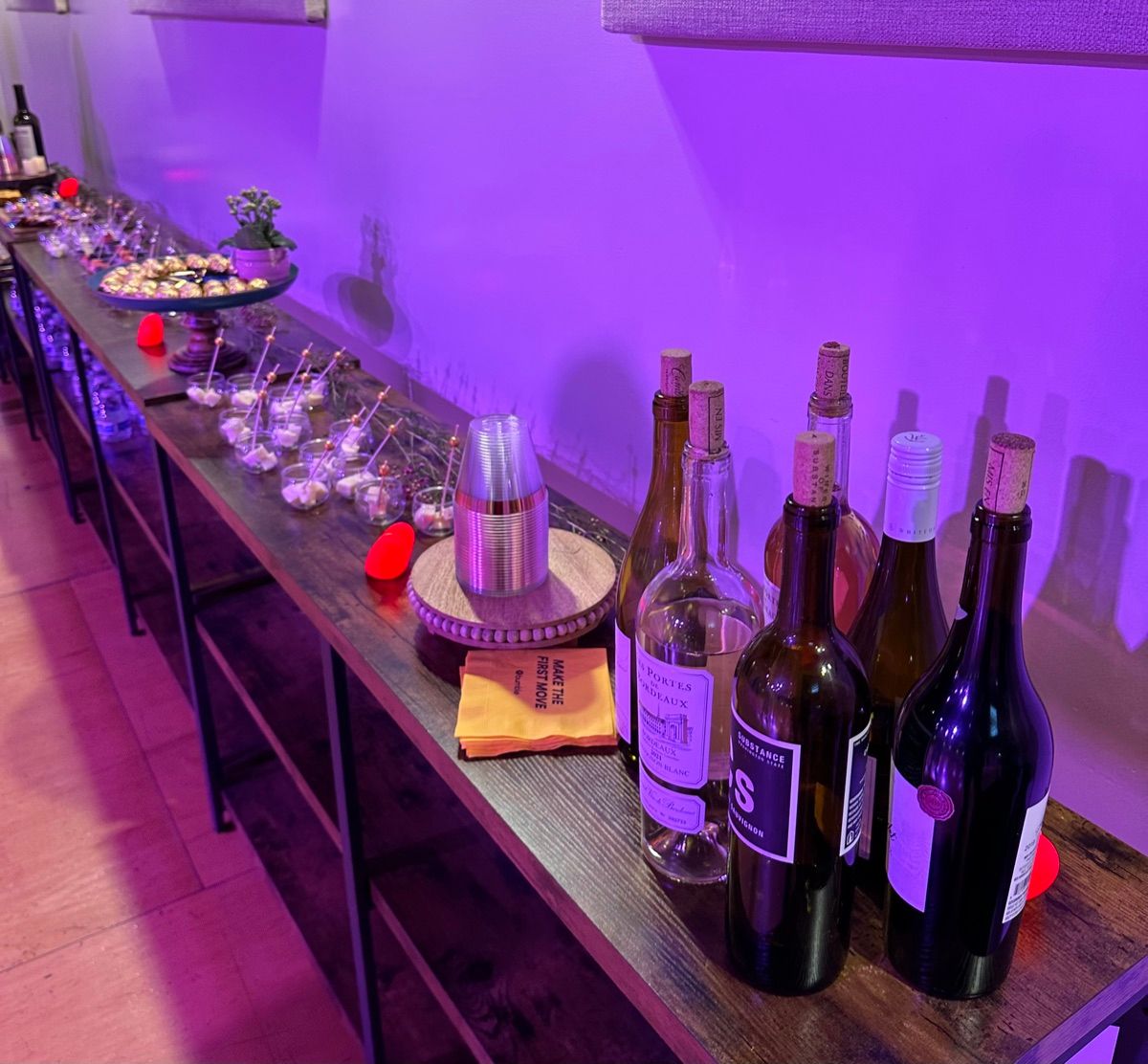 Wine bottles and glasses set out on a purple-lit bar before a Salsa Dance LA evening
