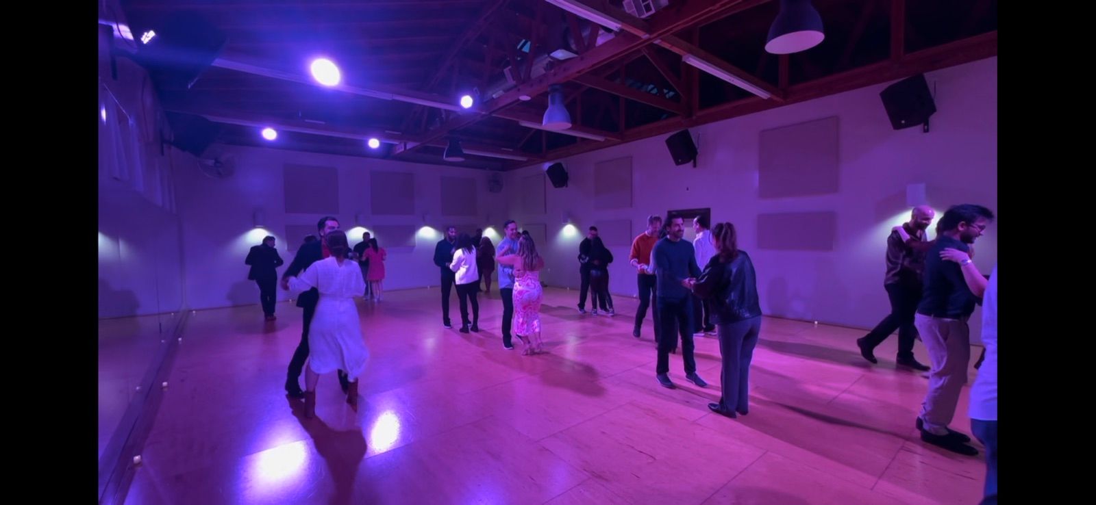 A full dance floor of couples at a purple-lit Salsa Dance LA workshop in Los Angeles