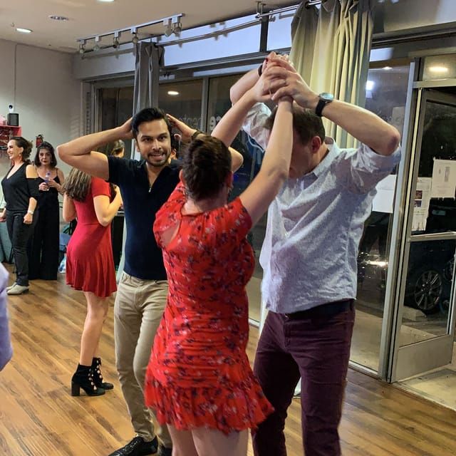 A couple mid-turn during a group salsa lesson in a Los Angeles studio as Avissh demonstrates behind them