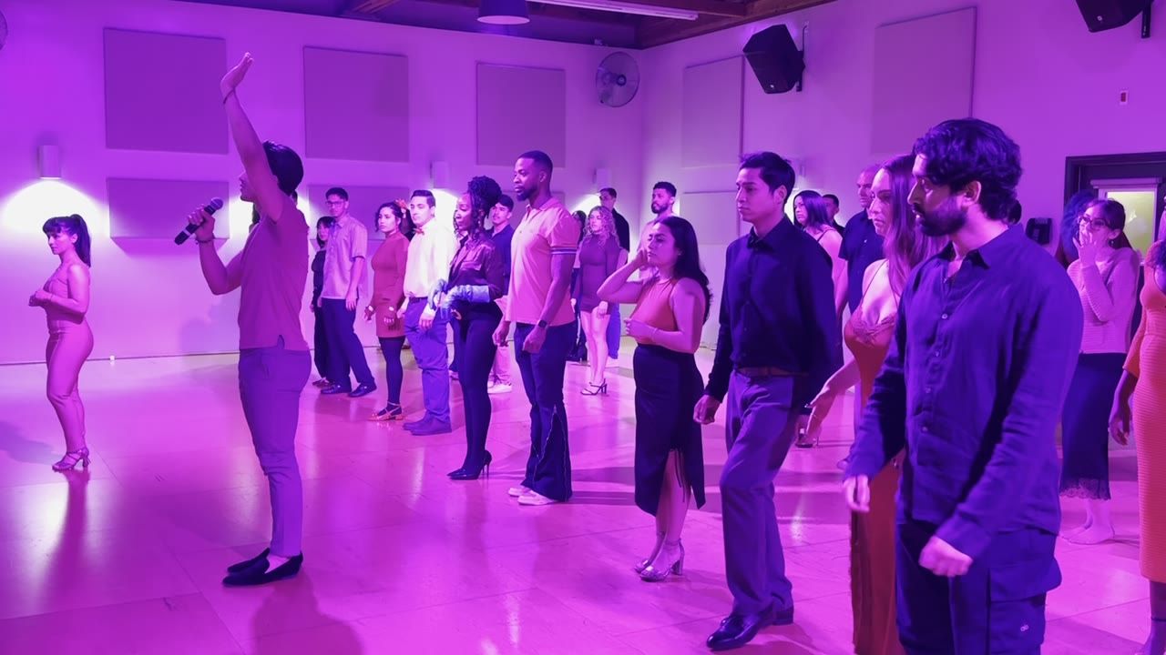 An instructor leading a packed salsa lesson from the front of the room at Rhythm & Romance in Los Angeles