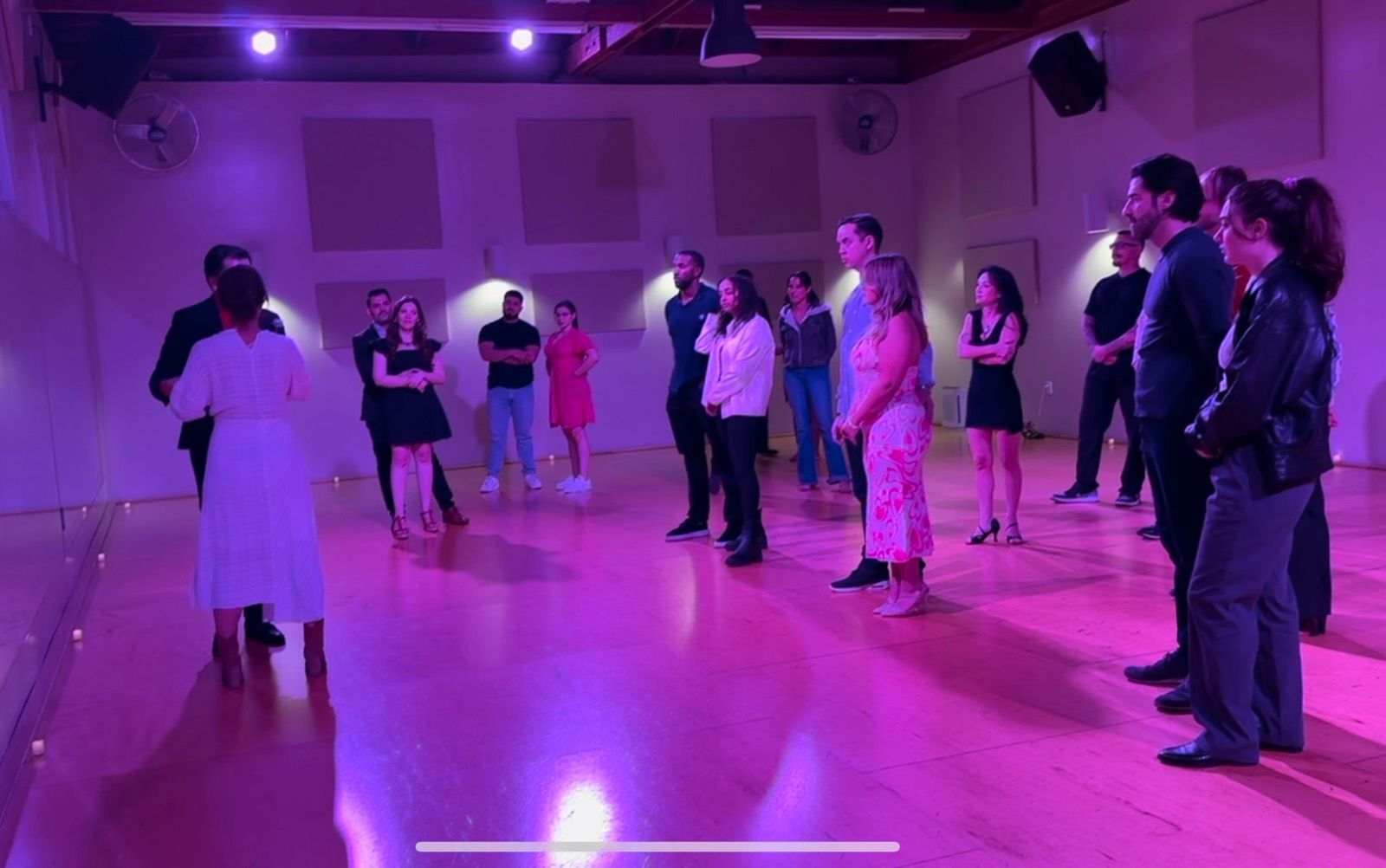 Couples dancing at a purple-lit Salsa Dance LA social in Los Angeles