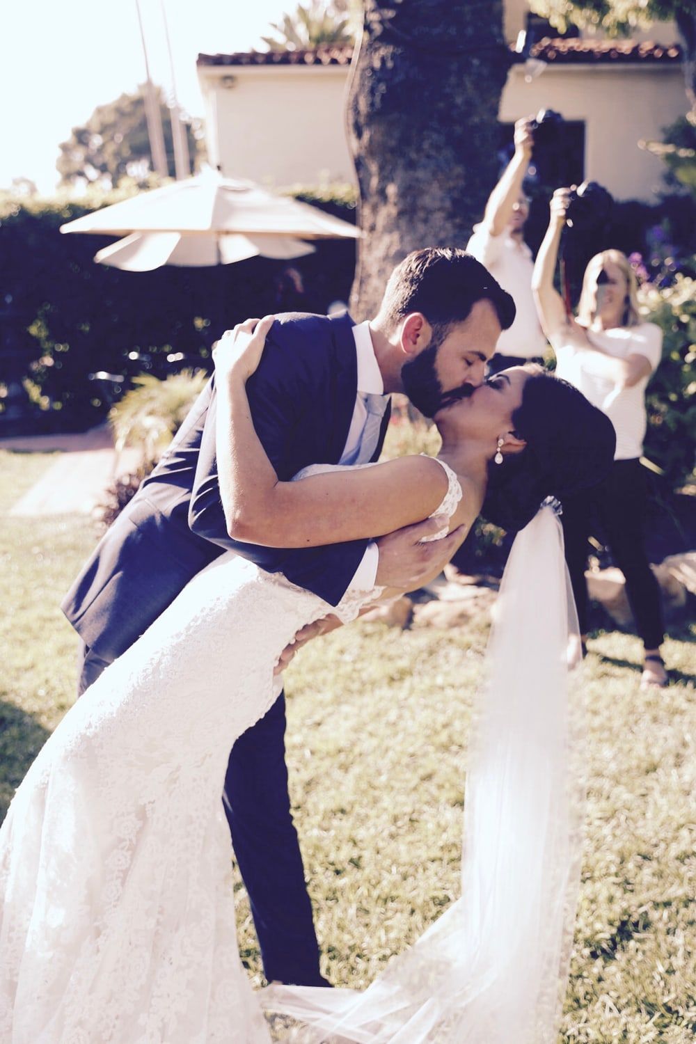 A newlywed couple finishing their dance with a dip and a kiss on an outdoor lawn